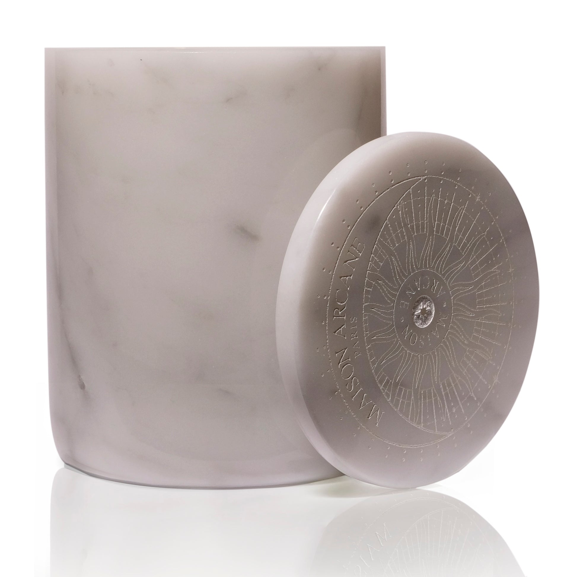 Bougie en marbre blanc avec couvercle gravé du logo posé sur le côté.