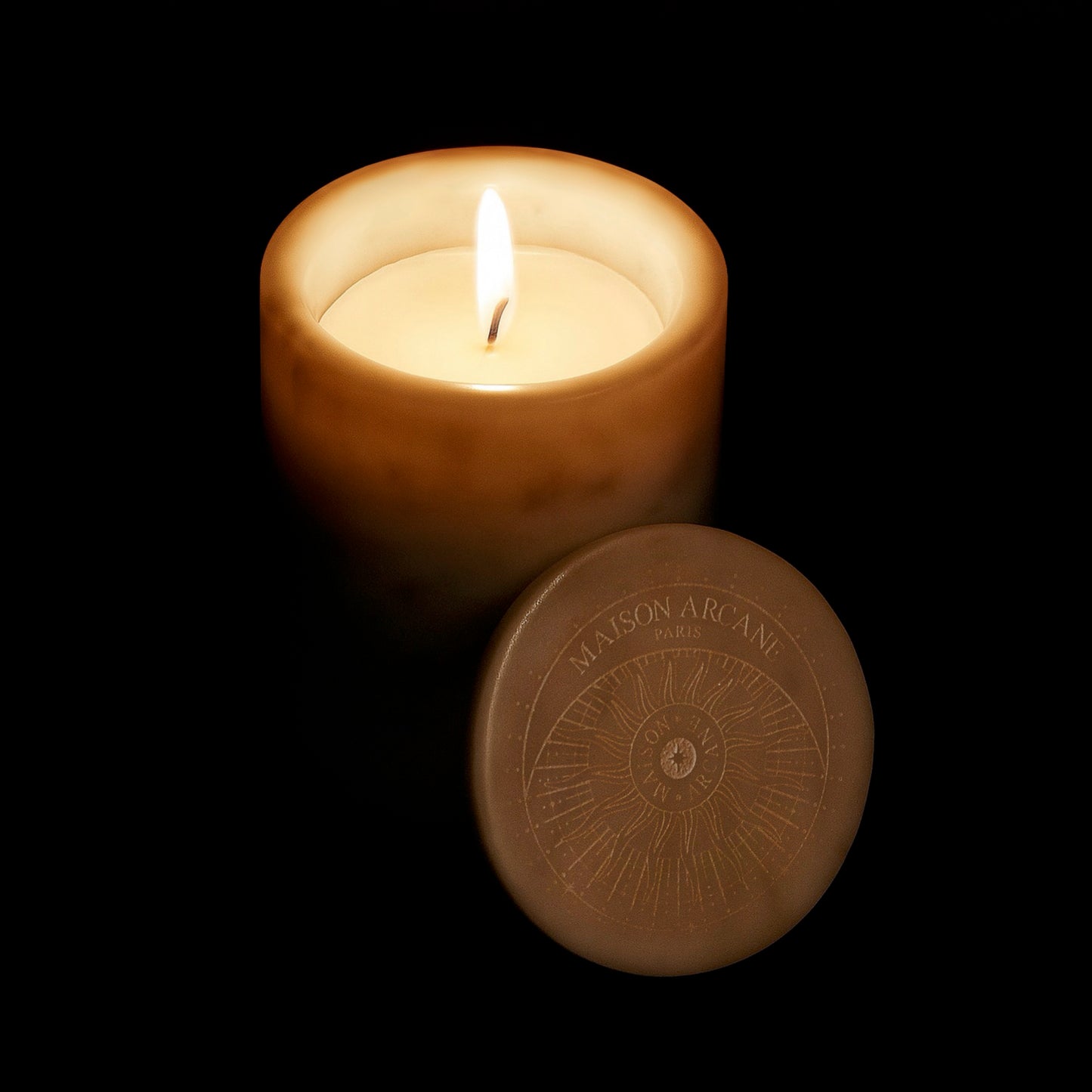 Bougie en marbre blanc allumée dans le noir diffusant une lumière douce et chaleureuse.