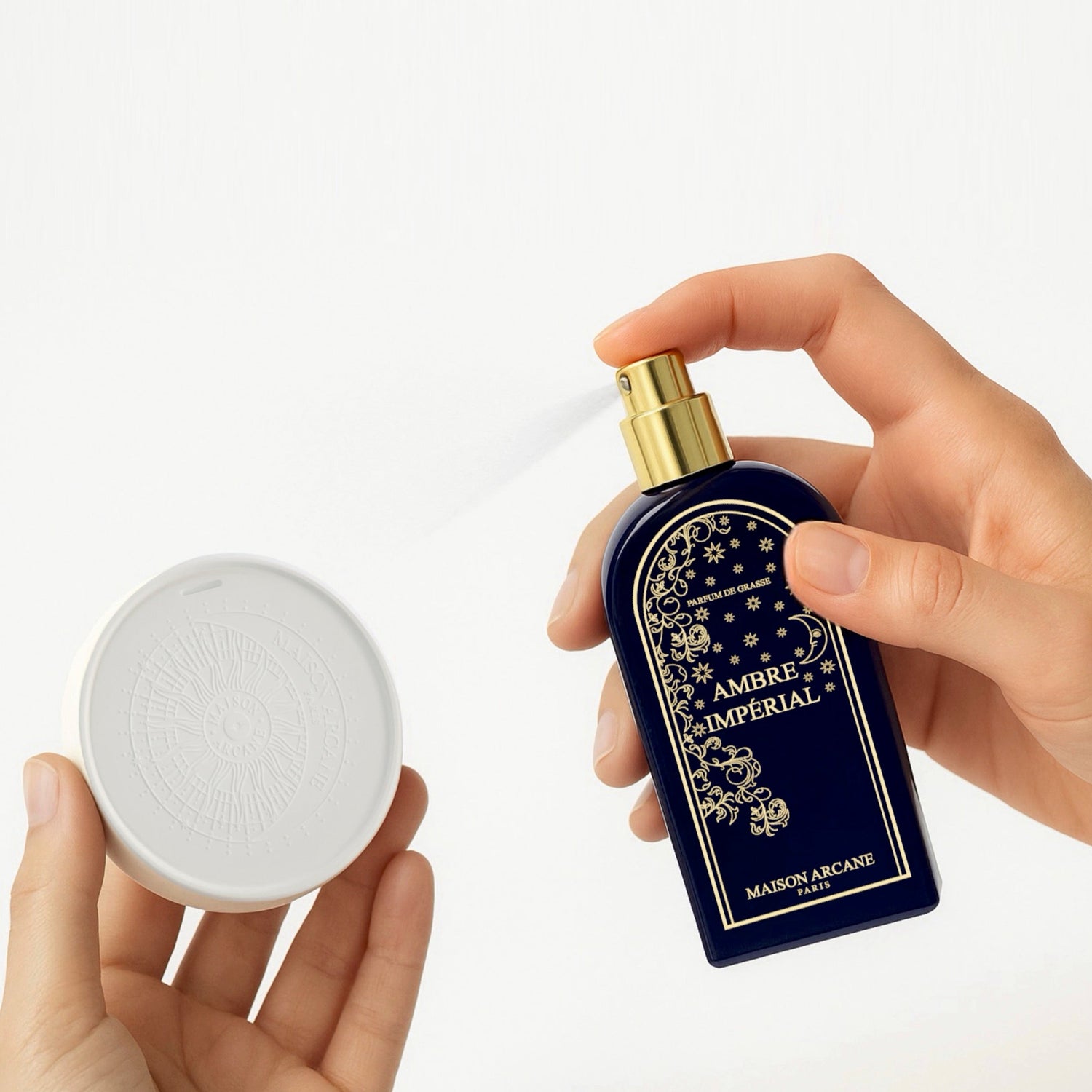 Parfum d'intérieur Ambre Impérial pulvérisé sur céramique à parfumer avec logo emblématique de Maison Arcane.