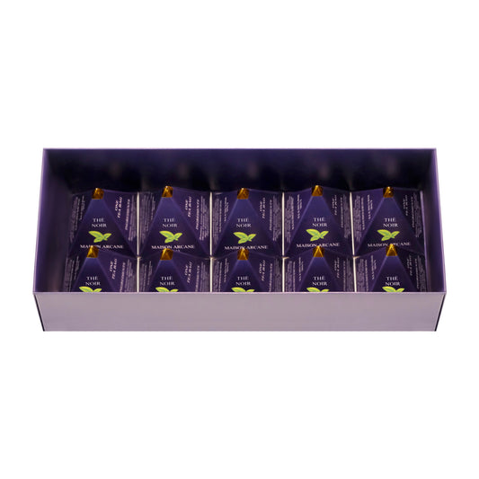 Vue intérieure d’un coffret de thé noir ouvert Maison Arcane avec infusions parfumées dans leur packaging pyramidal à la pointe dorée.