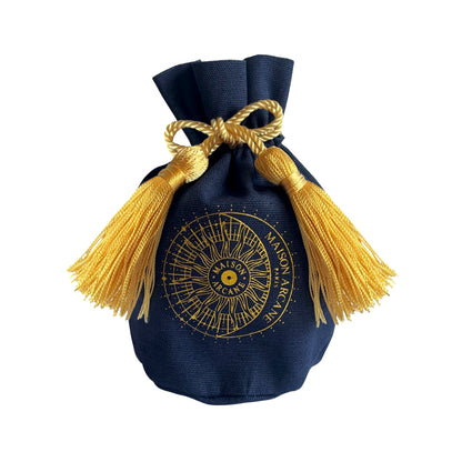 Pochon en coton bleu marine avec pompons dorés et logo Maison Arcane, packaging pour bougies miniatures.