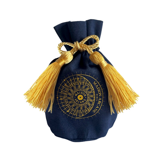 Pochon en coton bleu marine avec pompons dorés et logo Maison Arcane, packaging pour bougies miniatures.