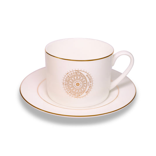 Tasse en porcelaine blanche gravée du logo doré Maison Arcane, agréable en main et idéale pour savourer les boissons du quotidien.